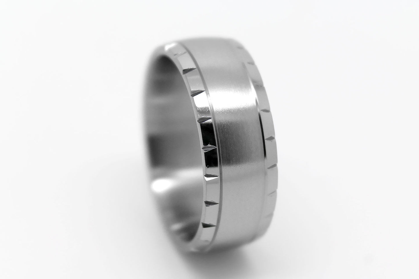 Titanium ring with brushed centre and polished filigree edge on a white background