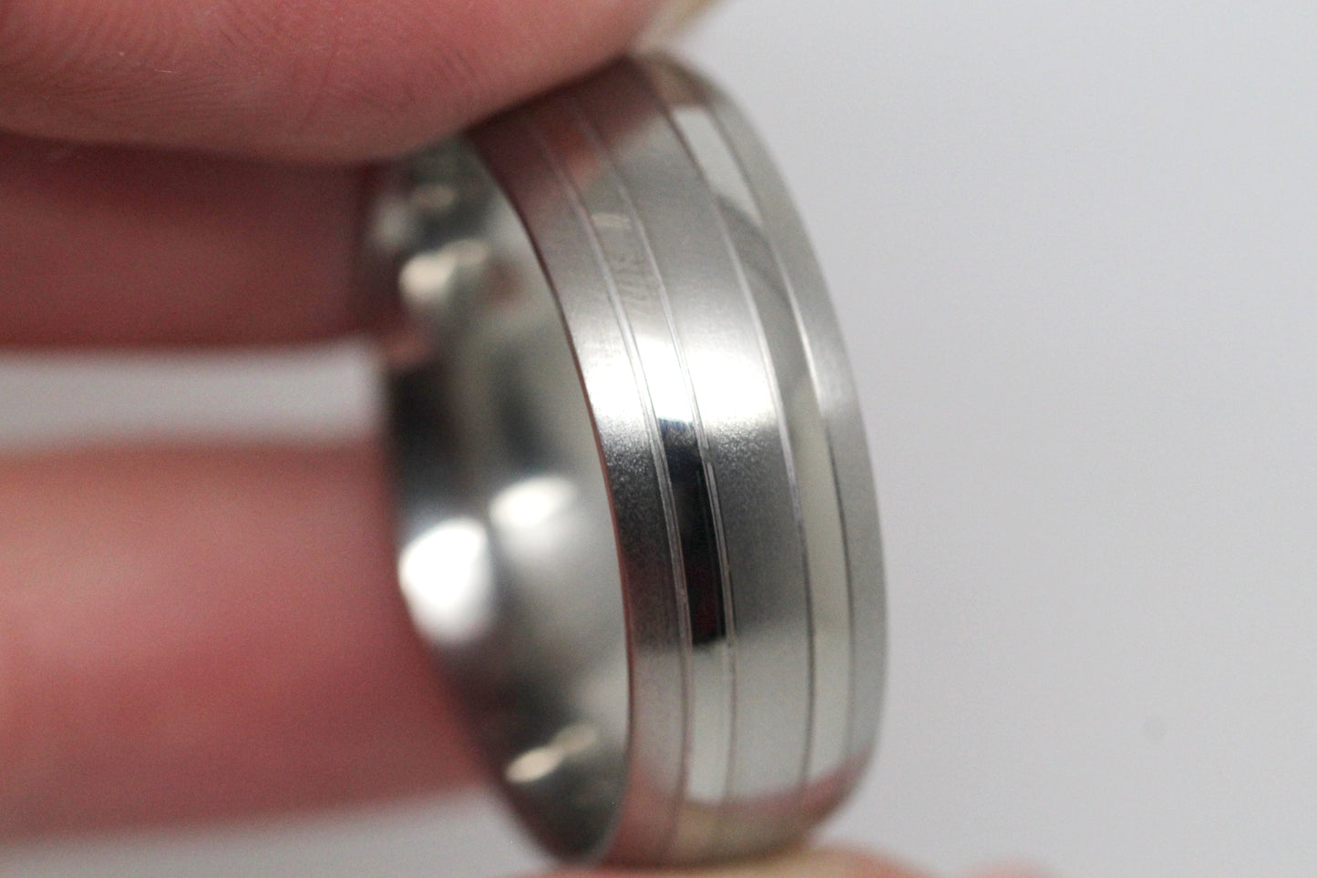 Titanium wedding ring for men and women, 8mm, featuring brushed finish and polished lines, showcased in hand.