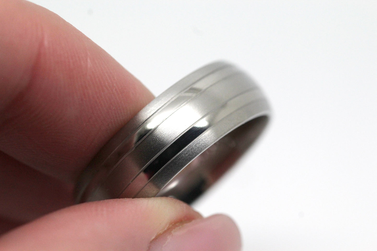 Matte Titanium ring held between fingers against a white background