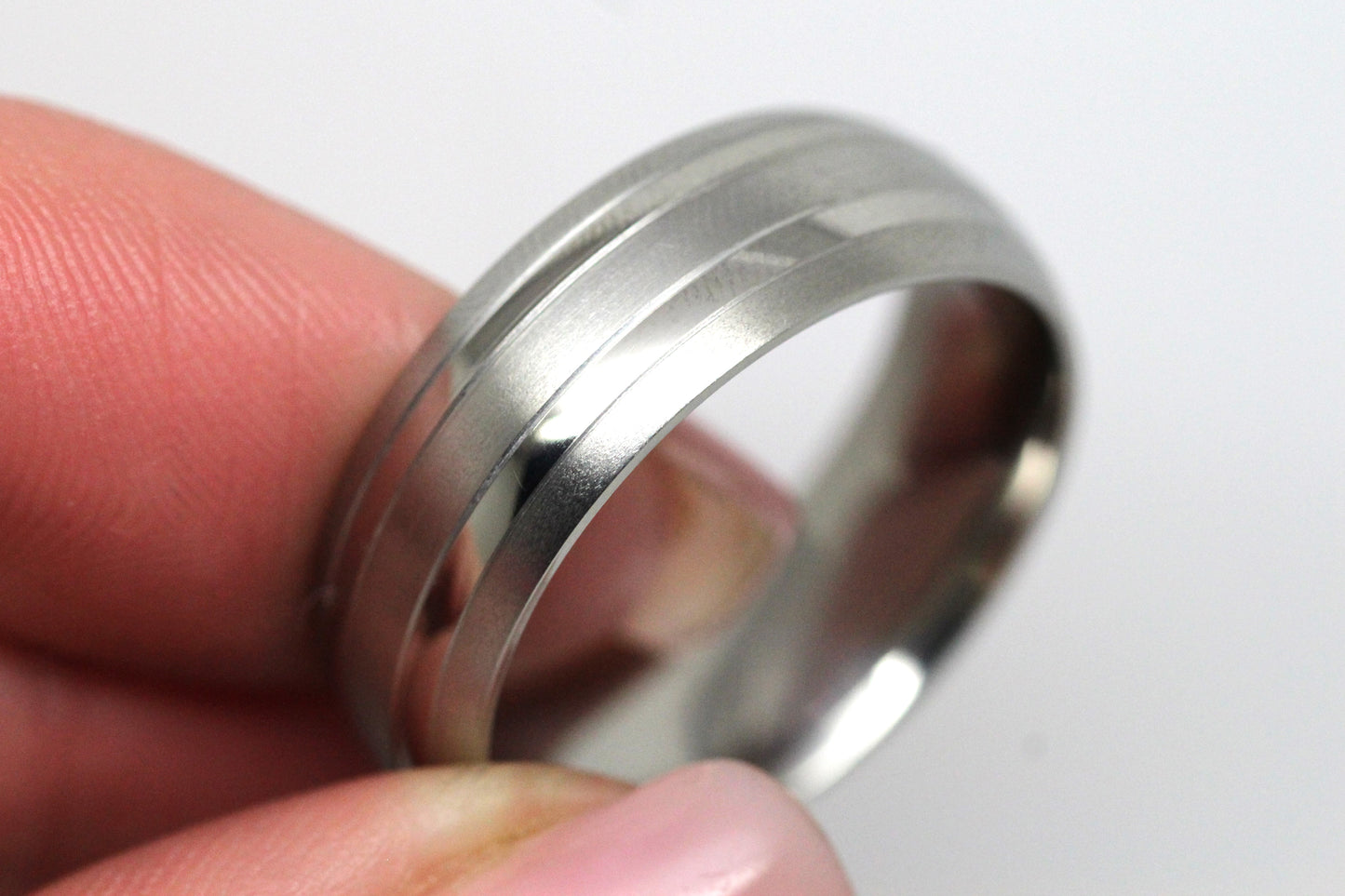 Titanium ring held between fingers on a white background