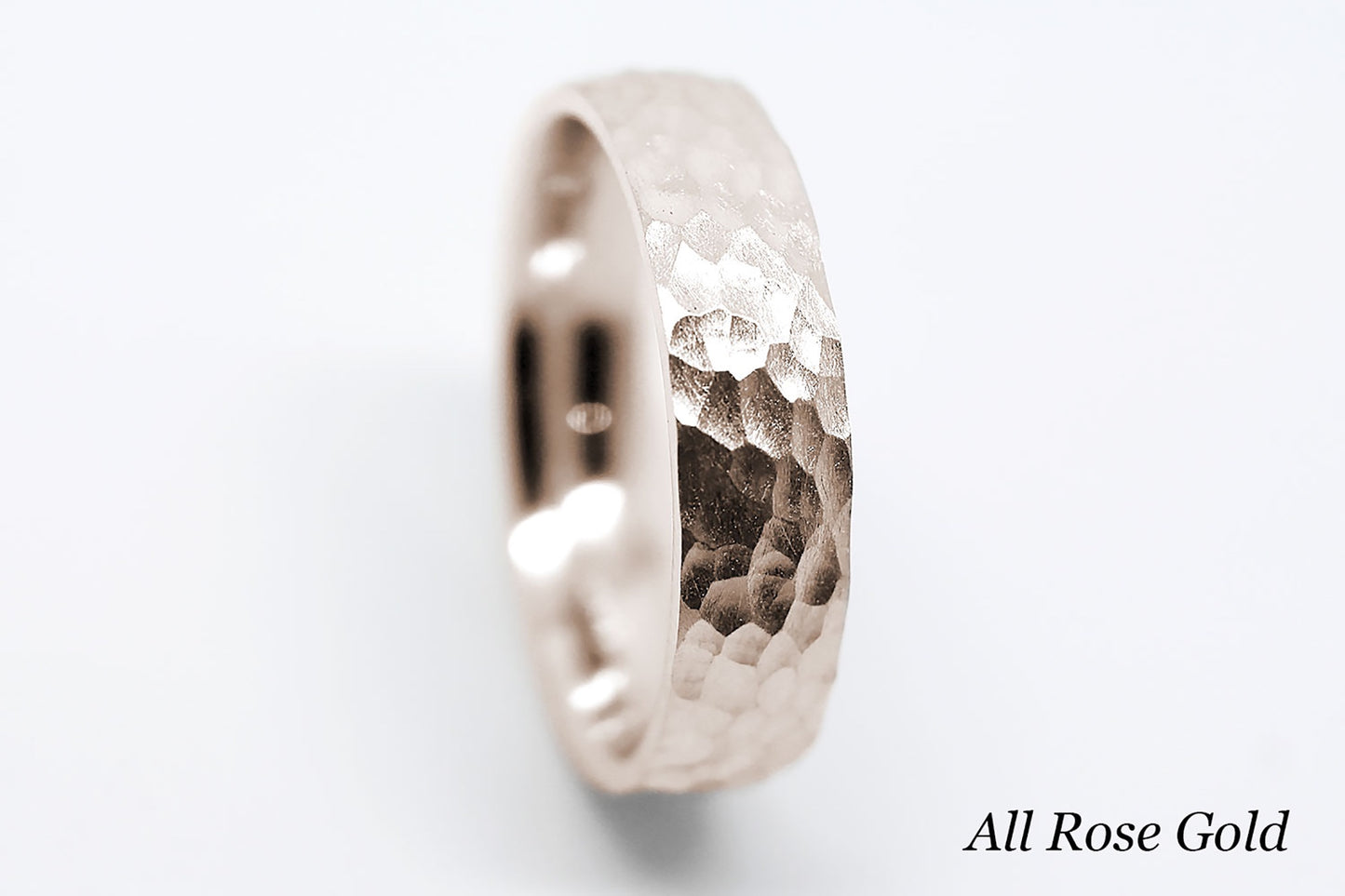 Rose gold ring with a hammered design on a white background.