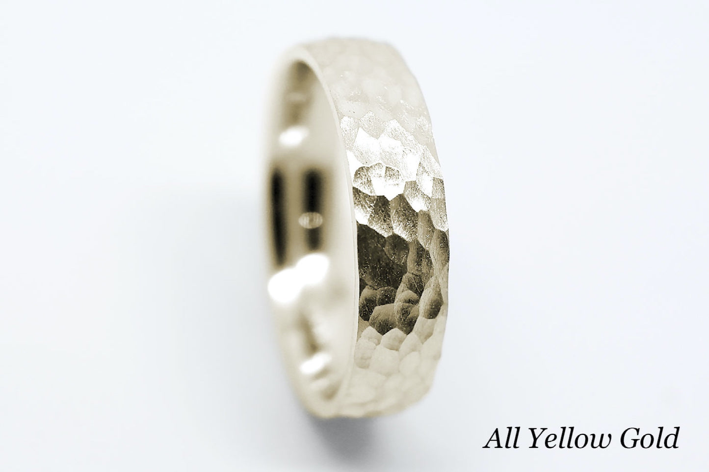 Hammered yellow gold ring on a white background.