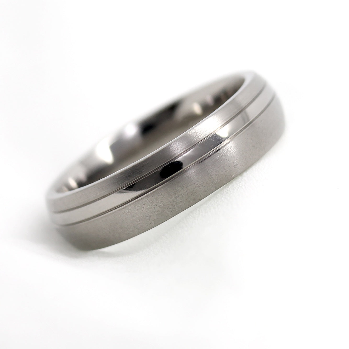 Titanium ring with a brushed finish and polished off centre line on a white background