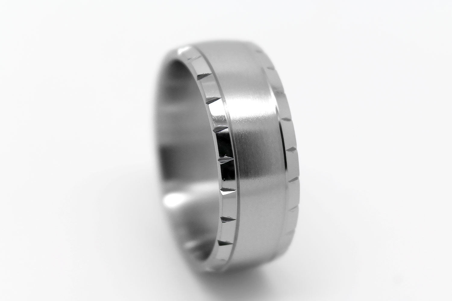 Titanium ring with brushed centre and polished filigree edge on a white background