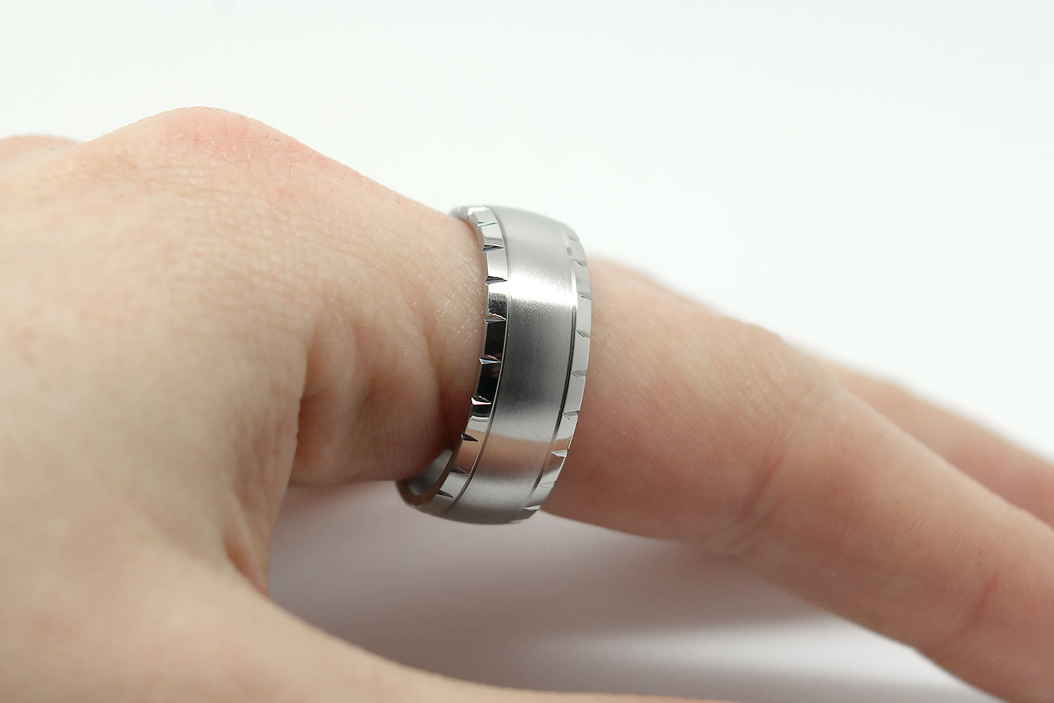Titanium ring on a finger against a white background