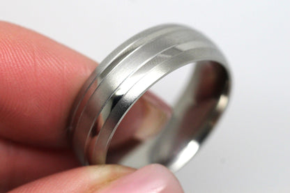 Titanium ring held between fingers on a white background