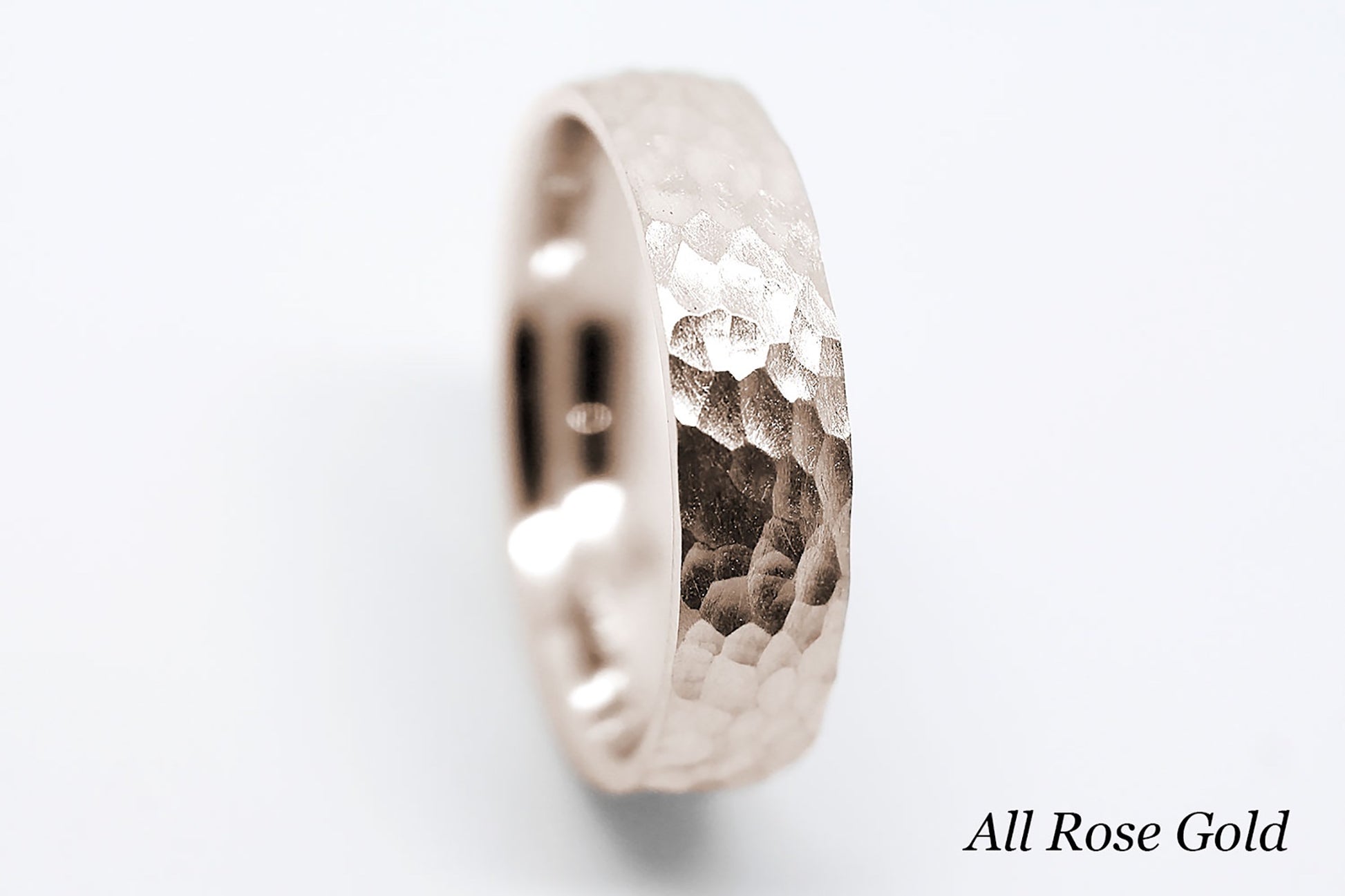 Rose gold ring with a hammered design on a white background.