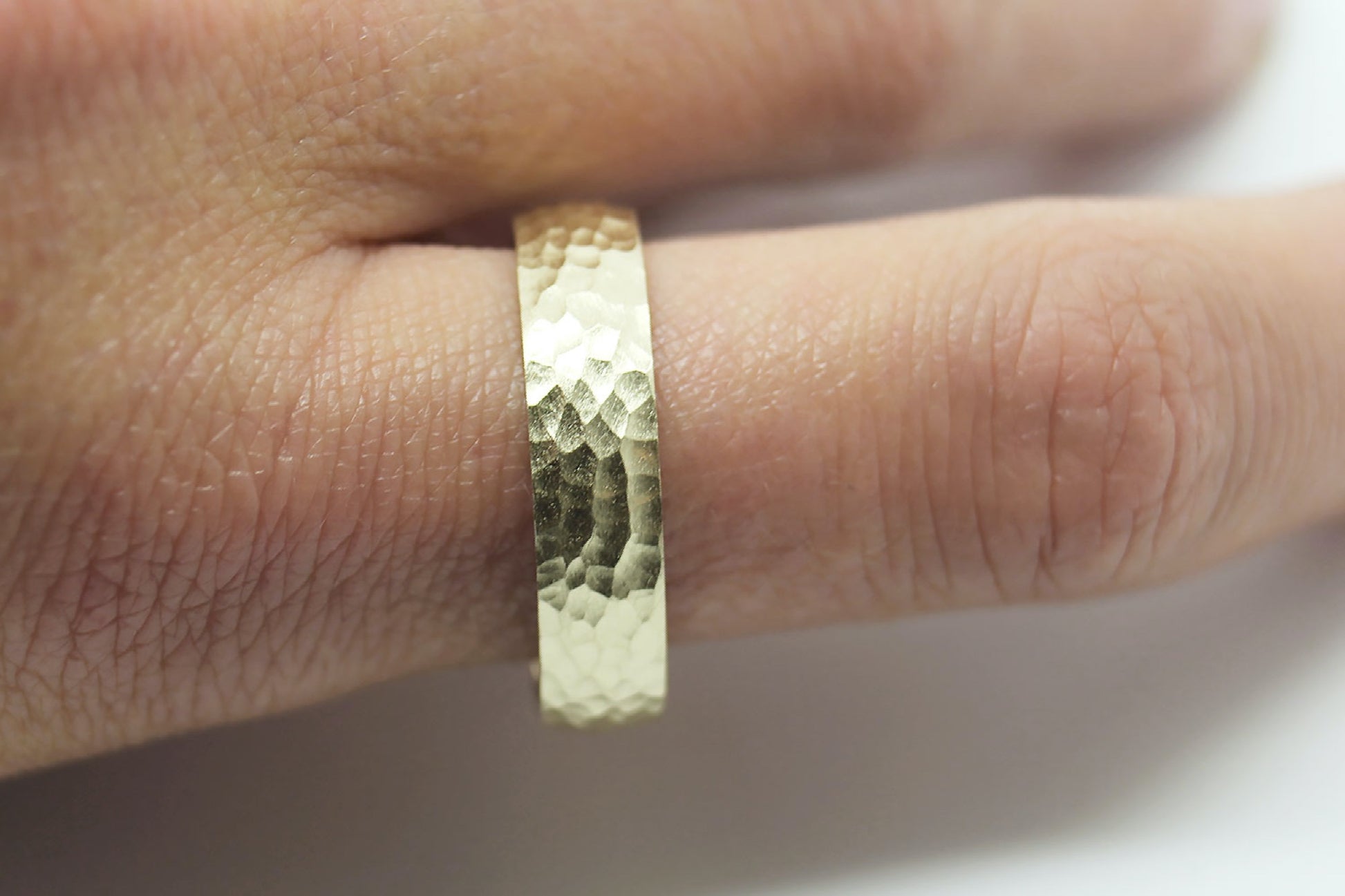 Hammered gold ring on a finger