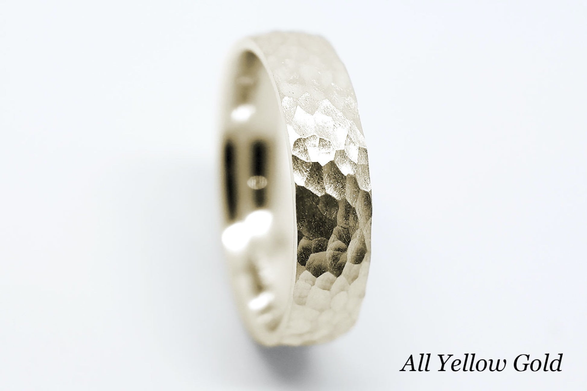 Hammered yellow gold ring on a white background.