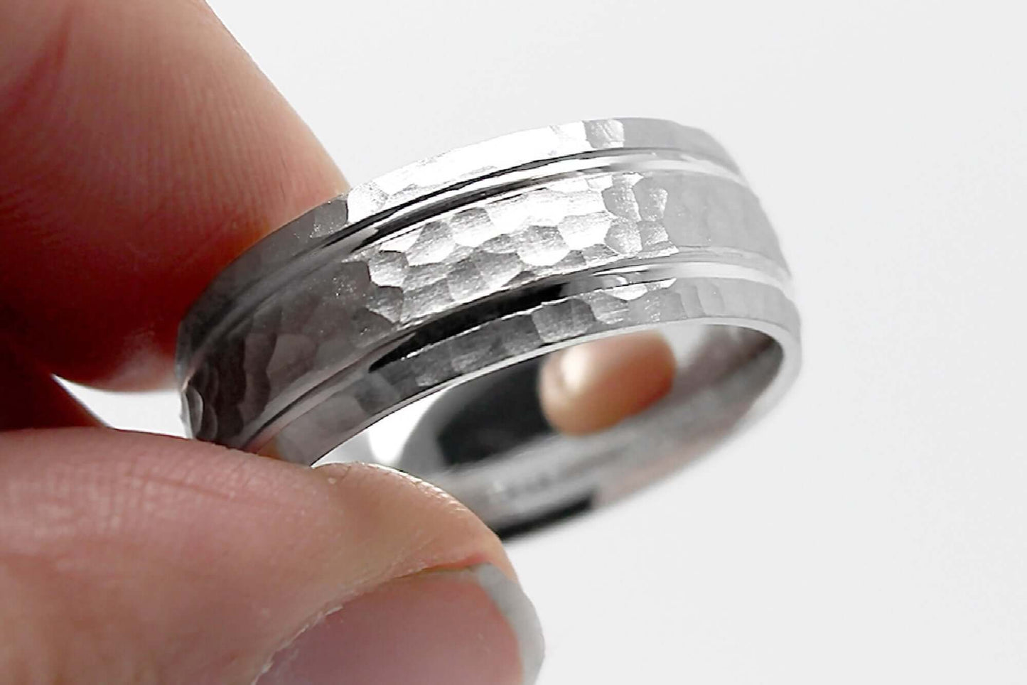 8mm wide Solid white gold ring for men featuring hammered finish and polished lines. Ring is her with fingers