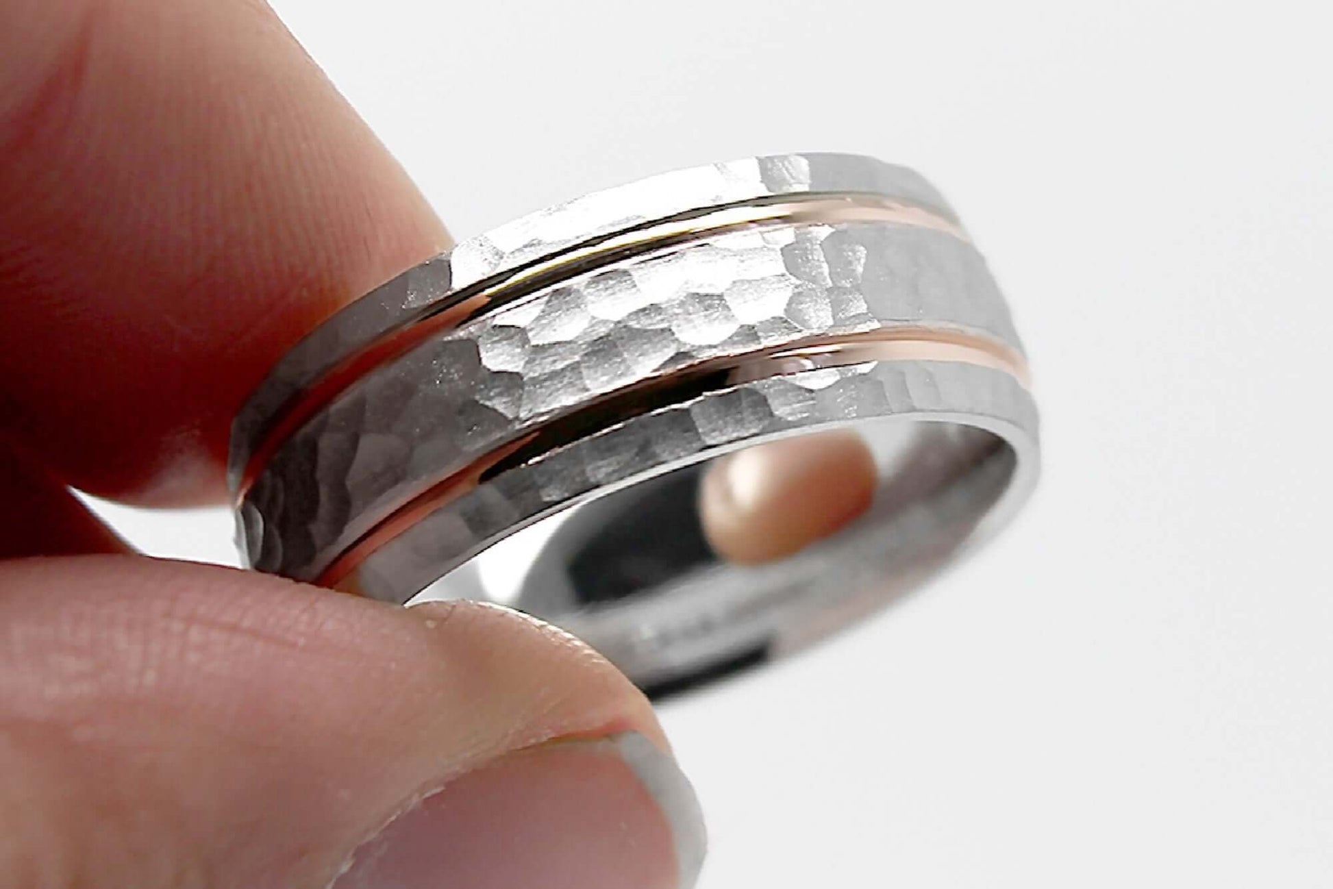 8mm wide Solid white gold ring for men featuring hammered finish and rose gold polished lines, held with fingers